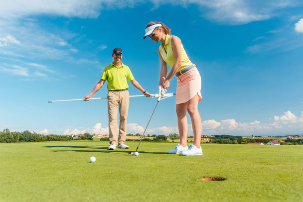 Volledige lengte van vrouw golfen met haar mannelijke match-partner  - Foto, afbeelding