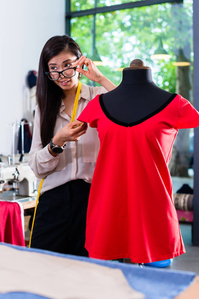 tailleur asiatique ajuste la conception de vêtement sur mannequin dans son atelier
 - Photo, image