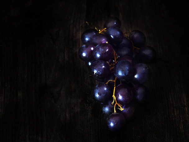 dark purple grapes on a dark brown wooden background with copy space - Фото, изображение