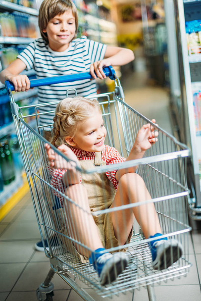 kids with shopping cart in supermarket - Foto, afbeelding