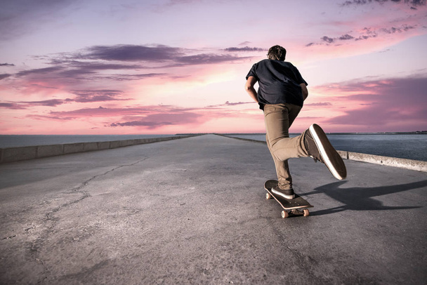 Skateboarder pushing on a concrete pavement - Фото, изображение