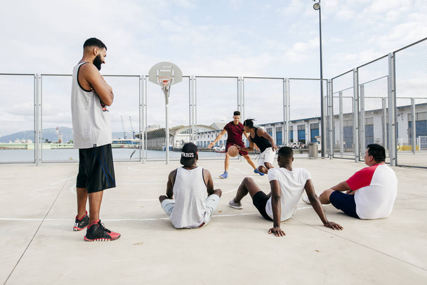 Hombres viendo a otros jugando baloncesto
 - Foto, Imagen