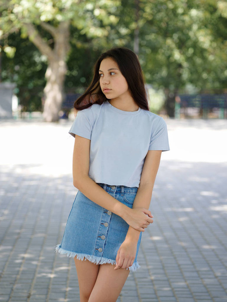 A cute young girl in casual clothes on a natural blurred background. Urban, fashion and youth concept. Copy space. - Foto, Imagen