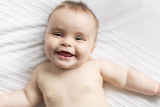 Cute happy 7 month baby girl in diaper lying and playing - Fotoğraf, Görsel