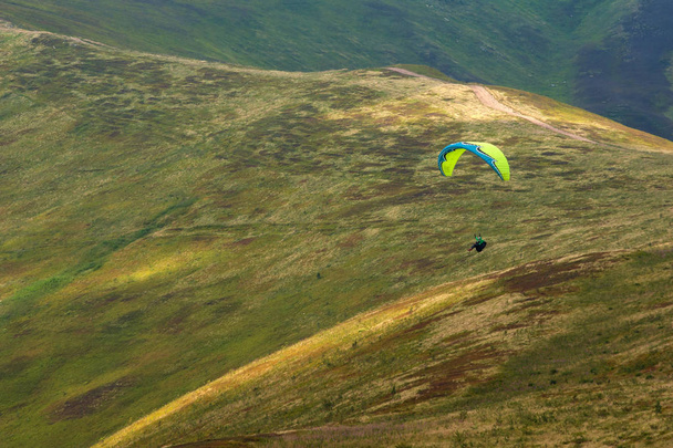 A paraglider fly over a mountain valley on a sunny summer day.  - Photo, Image