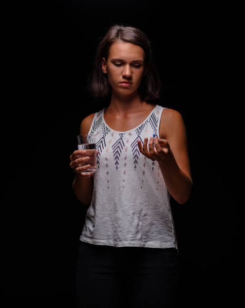 Woman taking antidepressants. A patient with pills on a black background. Stress, anxiety, depression treatment concept. - Foto, afbeelding