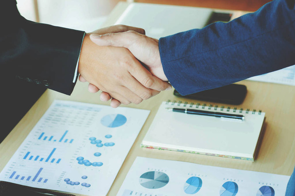 Two business men shaking hands with document background - Photo, Image