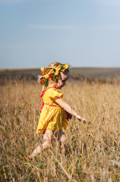 Pikkutyttö seppeleen kanssa pellolla
  - Valokuva, kuva
