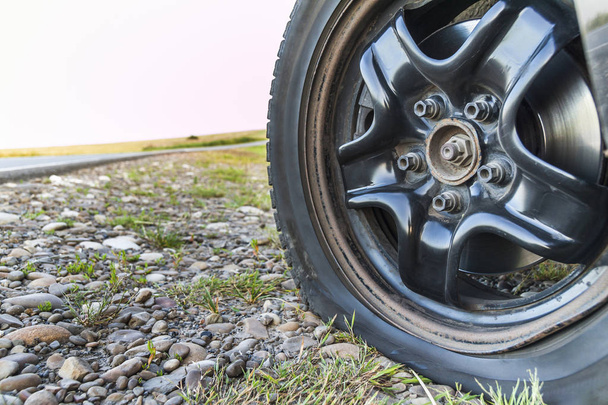 Gros plan d'un pneu crevé sur une voiture sur un chemin de gravier
. - Photo, image