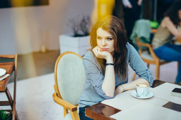 Young woman in a cafe. Shooting through the foreground - Fotografie, Obrázek