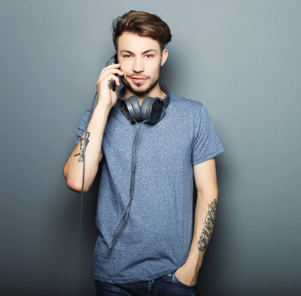 Handsome young man wearing headphones on his neck and smiling wh - Photo, image