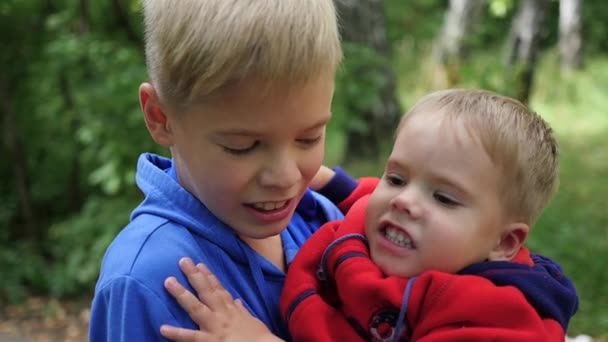 O menino abraça seu irmão mais novo e o segura em seus braços
 - Filmagem, Vídeo