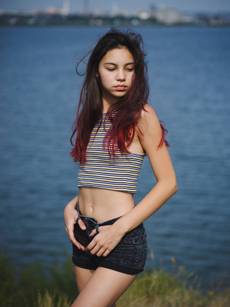 Beautiful, sensual girl walking near the river. A stylish teen on a blurred natural background. Natural beauty concept. - Foto, Imagem