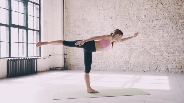 Beautiful yoga girl doing asanas in studio - Imágenes, Vídeo