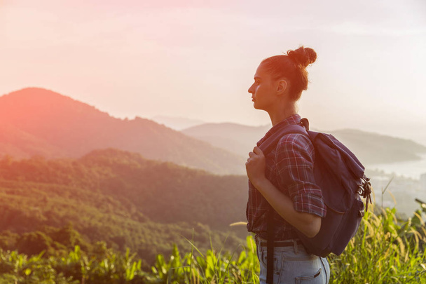 Hipster young girl with backpack enjoying sunset on peak of foggy mountain. Tourist traveler on background view mockup. Toned, Instagram filter - Photo, Image