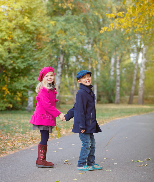 Children walking in beautiful autumn park on warm sunny fall day. - Photo, image