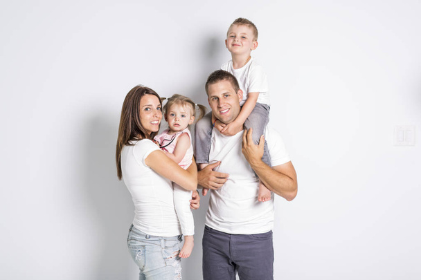 Ευτυχισμένη οικογένεια με δύο παιδιά σε studio γκρι φόντο - Φωτογραφία, εικόνα