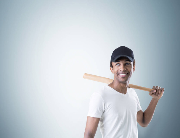 Smiling African American guy with a bat, gray - 写真・画像