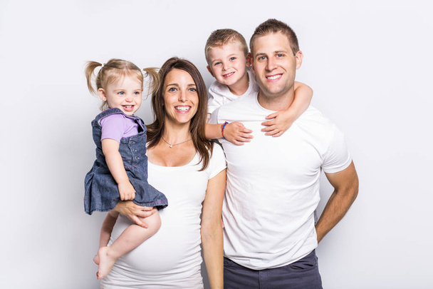 Happy family with two kids on studio gray background - Фото, изображение