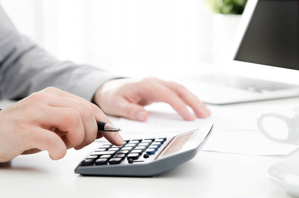 Accountant calculates tax. Working in the office with calculator - Photo, image