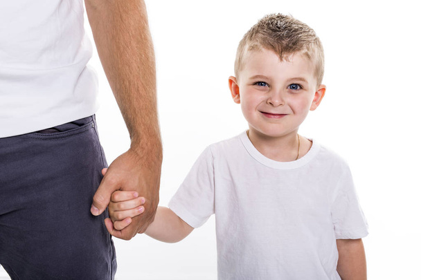 Boy holding hands of his father standing against white background. - Φωτογραφία, εικόνα