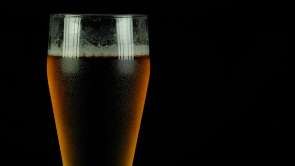 Verter Cerveza Primer plano. Pinta de cerveza artesanal fría aislada sobre fondo negro. Rotación 360 grados. 4k Uhd
 - Metraje, vídeo