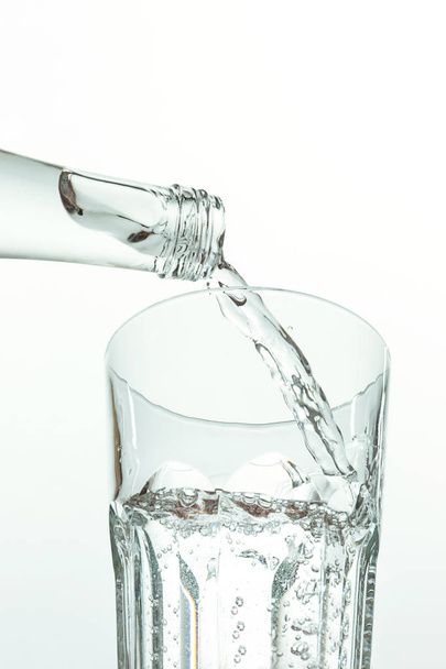 Pouring water from bottle into glass on white - Foto, Bild