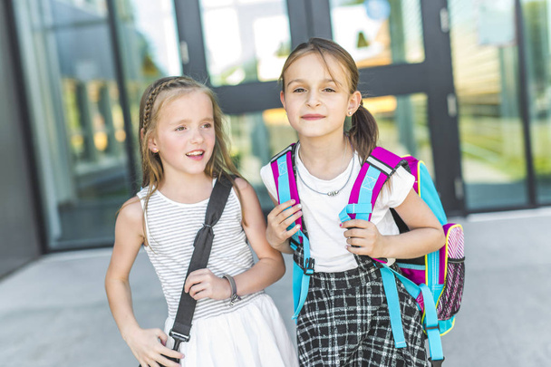 zwei Mädchen stehen mit Büchertaschen vor der Schule - Foto, Bild