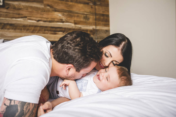 Loving parents with their cute little boy on bed - Photo, Image