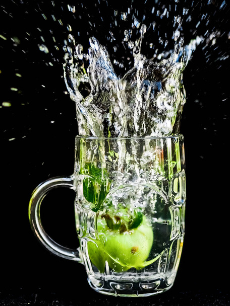 Water splash close-up macro van de kers als het stort in het glas water. - Foto, afbeelding