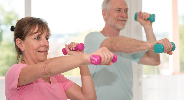 Senior couple exercising with dumbbells - Photo, Image