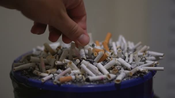 男はタバコいっぱい灰皿にタバコの吸い殻を出しています。手をクローズ アップ - 映像、動画