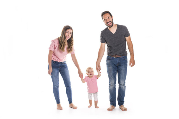 Couple of young parents helping their baby to make first steps on floor in their home - Φωτογραφία, εικόνα