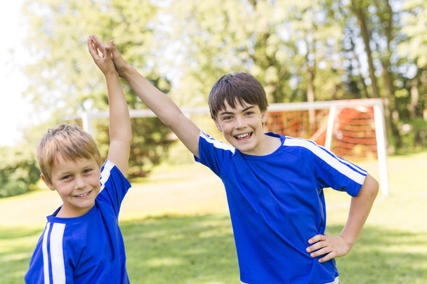Два мальчика с футбольным мячом в спортивной форме
 - Фото, изображение