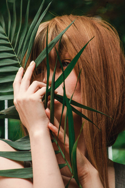 A girl looks into the distance through the palm branch - 写真・画像