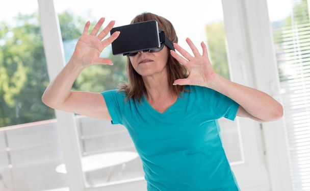 Γυναίκα μέσω σετ κεφαλής εικονικής πραγματικότητας - Φωτογραφία, εικόνα