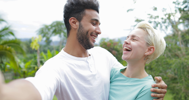 Paar macht Selfie-Foto umarmt Lachen im Freien über tropischen Wald, junger Mann und Frau glücklich lächelnd im Gespräch - Filmmaterial, Video