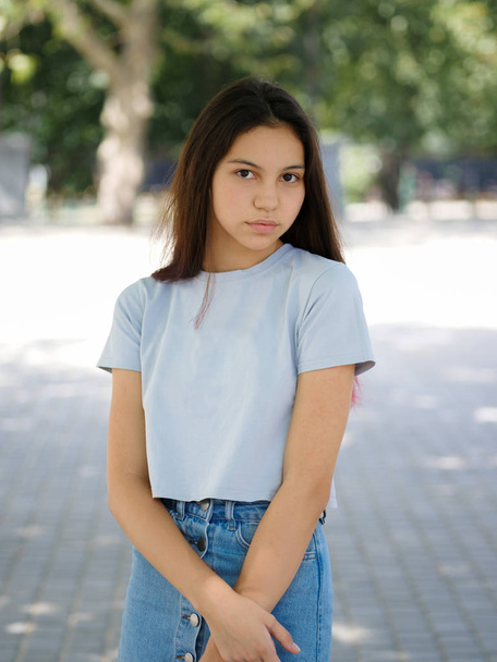 A cute young girl in casual clothes on a natural blurred background. Urban, fashion and youth concept. Copy space. - Zdjęcie, obraz