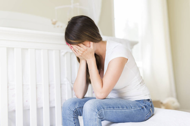 Depressed young woman in baby room - Φωτογραφία, εικόνα