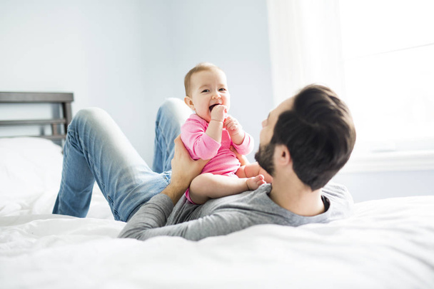 happy father playing with adorable baby in bedroom - Foto, imagen