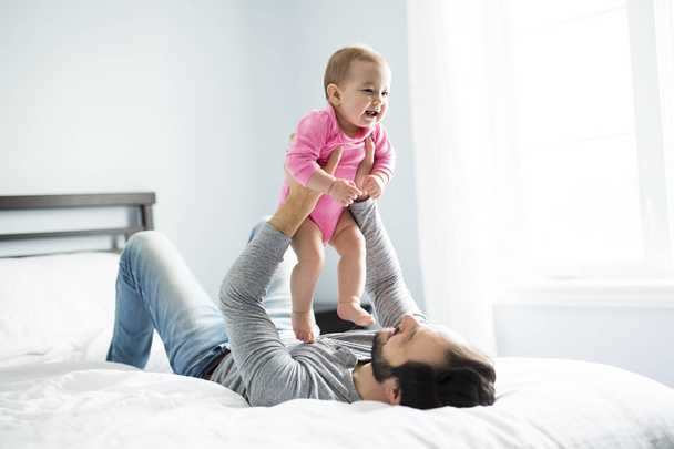 happy father playing with adorable baby in bedroom - Φωτογραφία, εικόνα