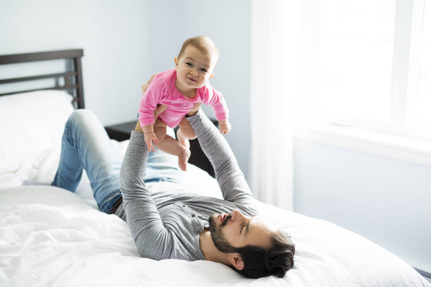 happy father playing with adorable baby in bedroom - 写真・画像