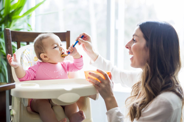 Mother feeding baby with spoon - Zdjęcie, obraz