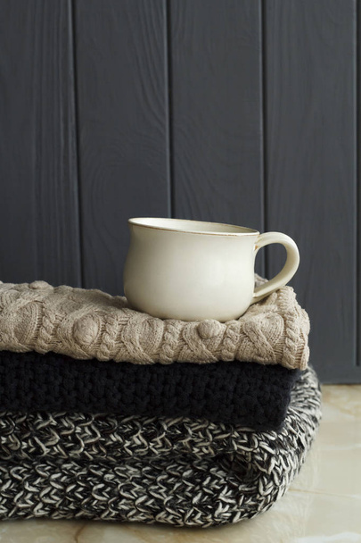 Picture of cozy sweaters and cup of coffee or tea over grey back - Foto, immagini