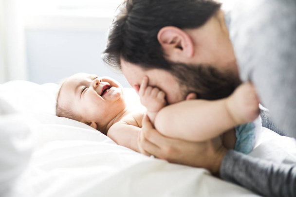 happy father playing with adorable baby in bedroom - Photo, image