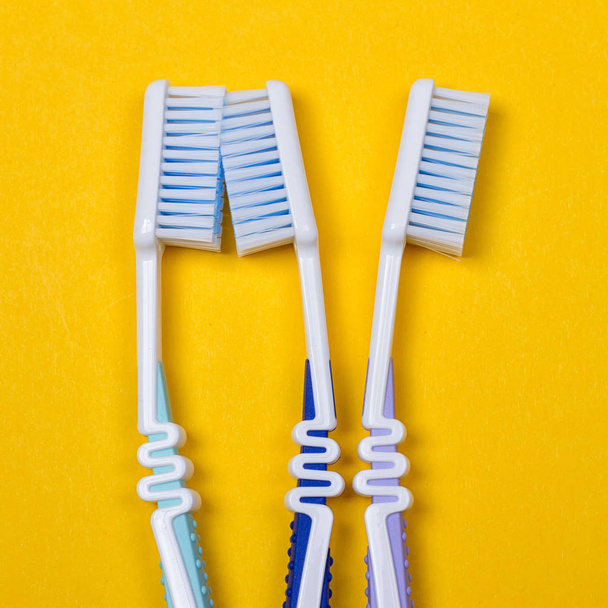 three Toothbrushes on yellow background - Photo, Image