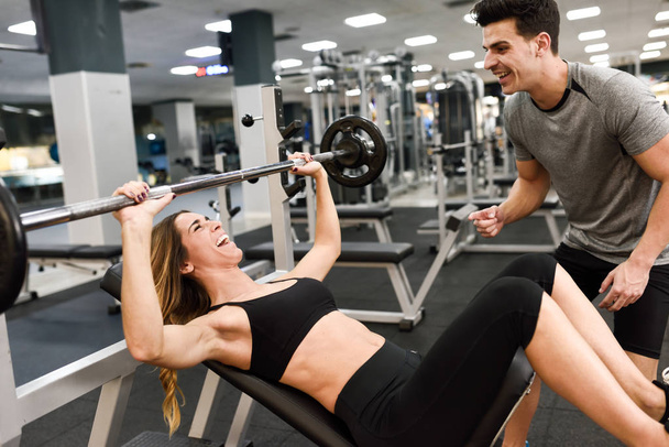 Persoonlijke trainer helpen van een jonge vrouw die lift gewichten - Foto, afbeelding