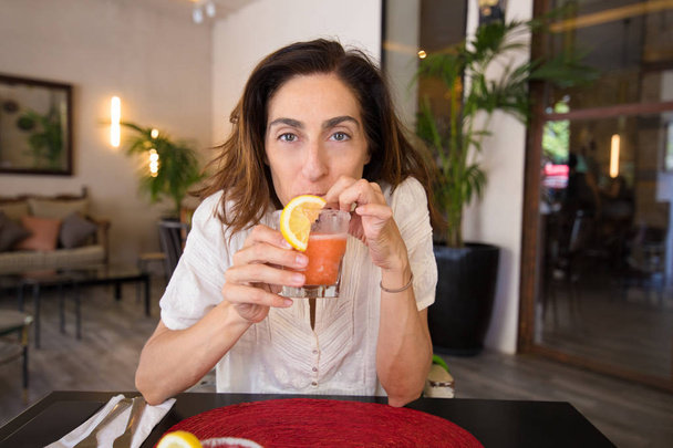woman drinking frozen strawberry margarita and looking - Фото, зображення