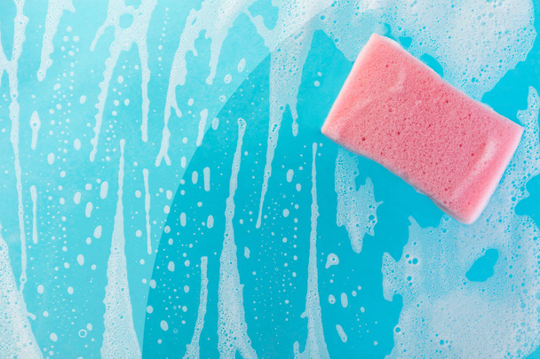 sponge in foam on a blue background - Foto, afbeelding