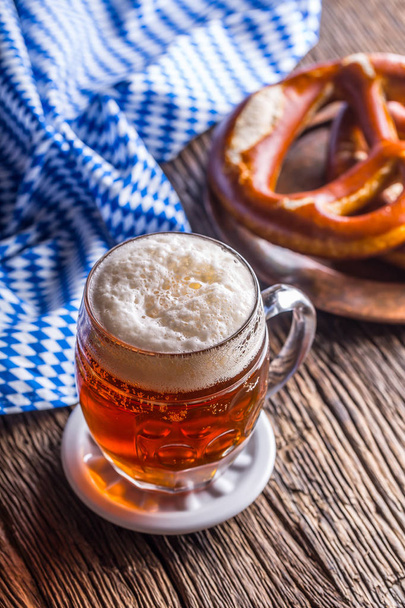 Beer and Oktoberfest. Draft beer pretzel and blue checkered tablecloth as traditional products for bavarian festival oktoberfest - Fotografie, Obrázek
